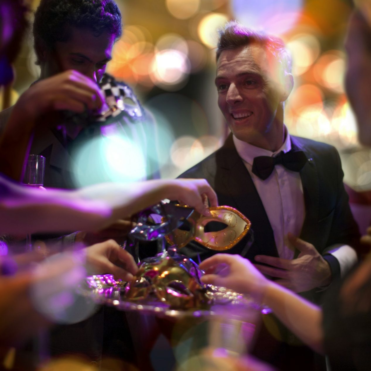 Man in tuxedo handing over eye masks on a costume party